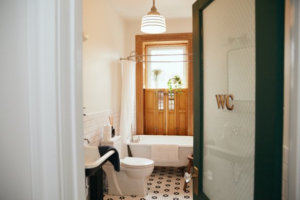 Door Opens to Bath With Wooden Window Above Vintage Clawfoot Tub