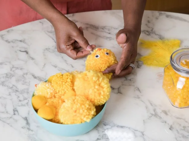 A yellow pompom is turned into a chick with the addition of googly eyes, a felt beak and a popsicle stick.