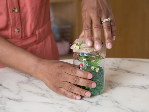 This glass jar has been decorated and filled to look like a magical meadow fairy garden.