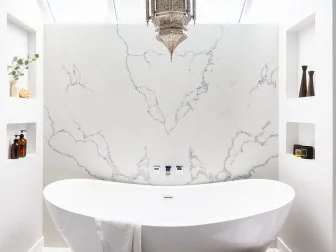 The bathtub is the focal point of the master bathroom. A marble backdrop and walls featuring cutout shelving create a nook that feels like a sanctuary. “For me, self-care means getting small moments of time back,” Breegan says. For an interior designer, TV personality and mom, getting those moments back is not only vital, it requires planning. This bathroom is definitely designed with that in mind. The massive soaking tub is ideal for reclaiming moments as the day slips away.