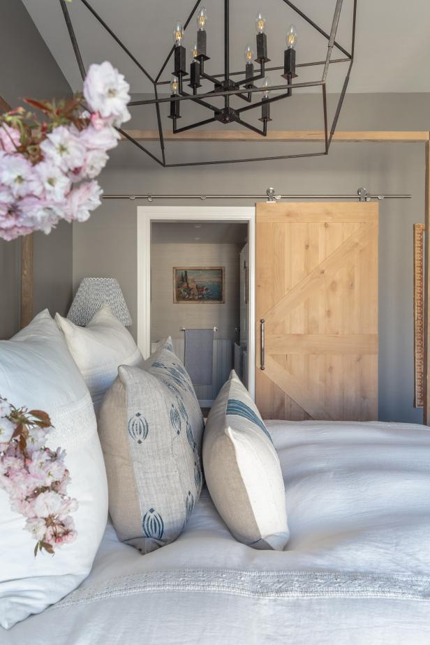 Neutral Bedroom With Modern Chandelier, Sliding Barn Door to Bathroom