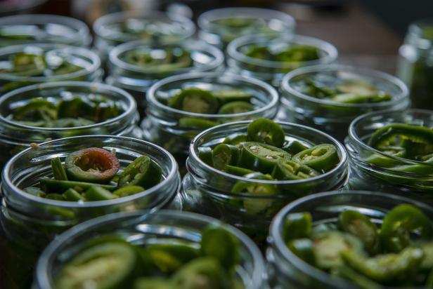Canning jars sit on a countertop waiting to be filled with jalapenos.