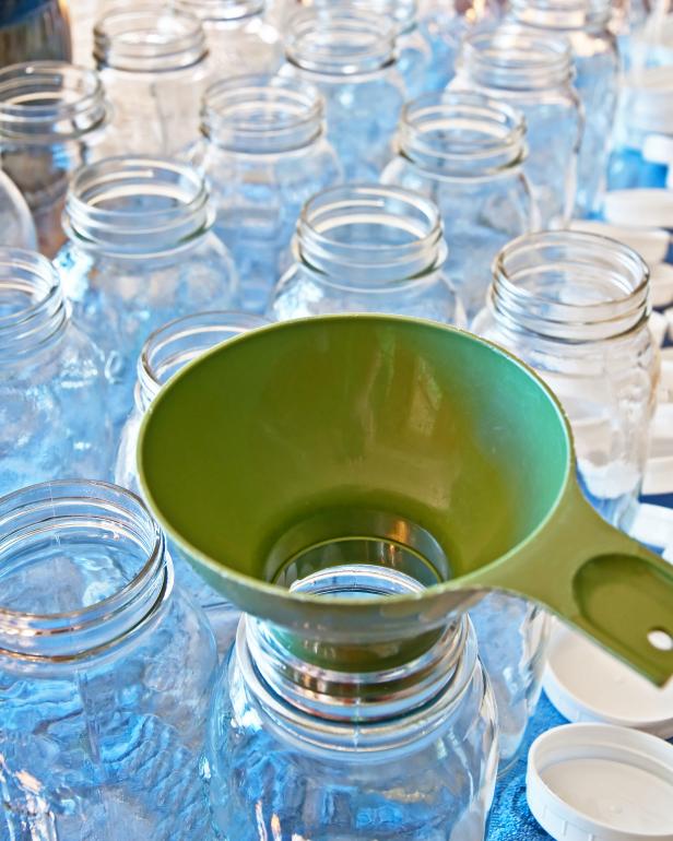 A green funnel is used to fill canning jars neatly.