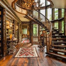 Massive Curved Stairway Situated Around a Rustic Chandelier Made of Antler Sheds