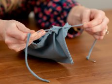 Pulling a drawstring through the top of a pouch.