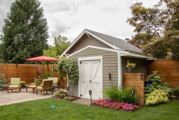 Repeating design elements, like the wooden wall attached to this shed that matches the one surrounding the yard, makes a shed fit into the landscape. Planting beds next to the shed makes it look like part of the garden.