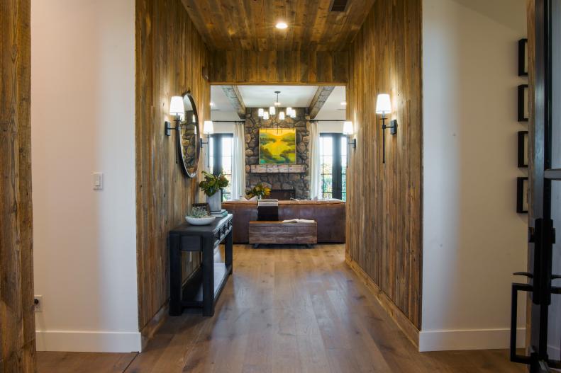 Nick said "It was the perfect entryway to the perfect house." He loved the rustic reclaimed siding. The cognac leather sofa, smooth river rock fireplace and rustic box beams make the open concept living area feel grand and cozy at the same time. The dual fireplace and flanking French doors lead to the family's new backyard.