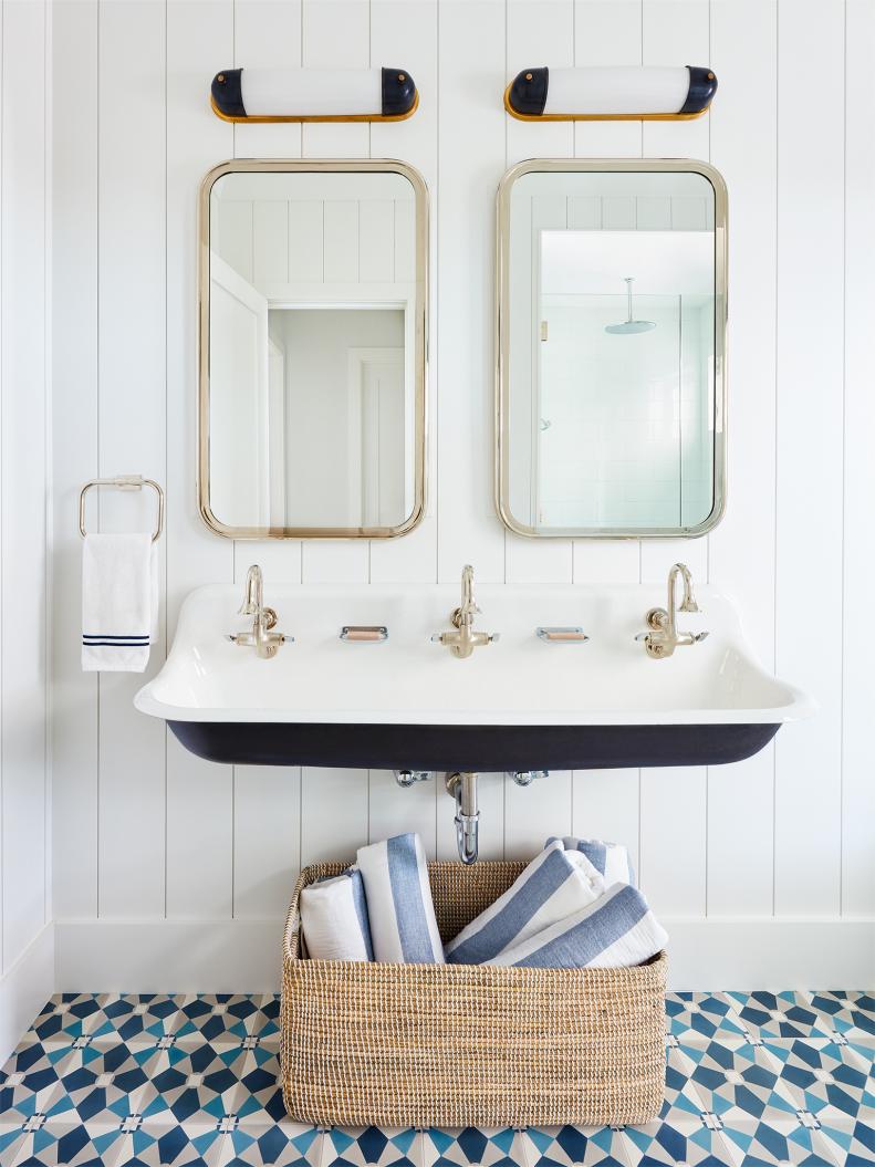 While this trough-like station is a great fit for a family with four kids in Jupiter, Florida, it’s also a statement piece, says designer Kara Hebert. She paired the black-and-white Kohler sink with Thomas O’Brien sconces that mimic the two-tone look. For a kick, she picked tiles by Cement Tile Shop in shades of blue. Mirrored medicine chests and a roomy basket provide storage. 