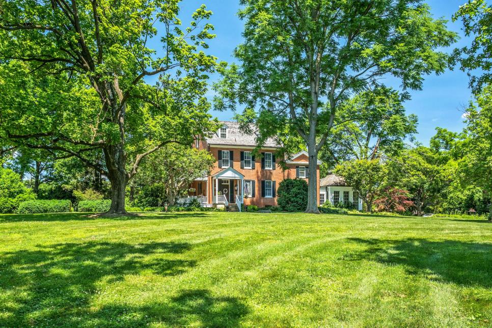 Brick Manor House In View Between Large Front Yard With Mature Trees