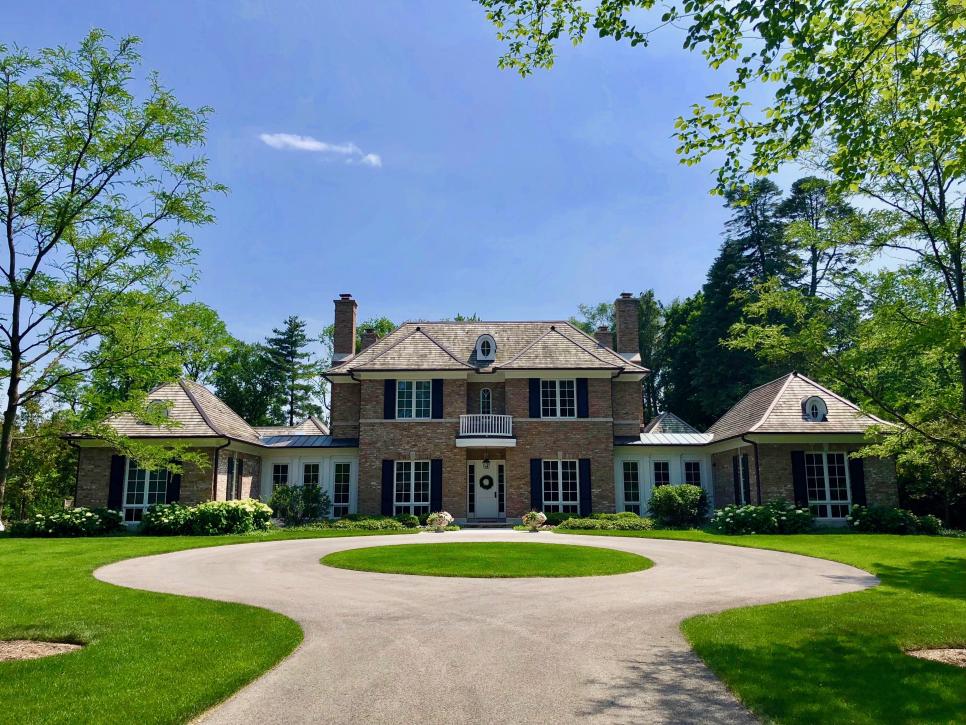 Circle Driveway to Colonial Home With Brick Facade and Black Shutters