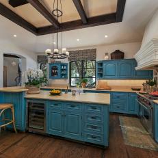 Spanish-Style Open-Plan Kitchen With Bold Blue Cabinetry and Exposed Beams
