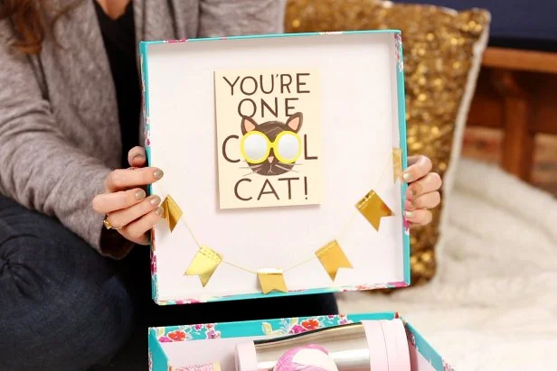 Pack all of the gifts in the box and add a finishing touch by taping a greeting card and miniature banner to the lid for an extra surprise when they open it up.