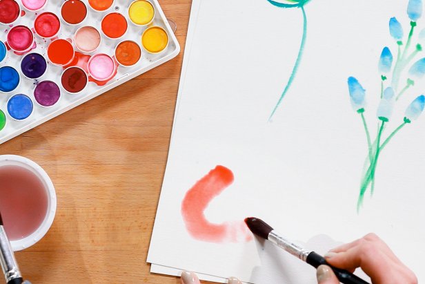 To paint a poppy, load up a large brush with water and red paint and draw a circular flower shape. Use a paper towel or washcloth to soak up the excess water.