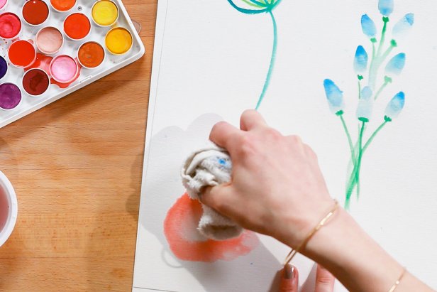 To paint a poppy, load up a large brush with water and red paint and draw a circular flower shape. Use a paper towel or washcloth to soak up the excess water.
