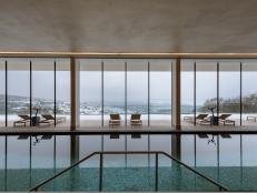 Windows over an indoor swimming pool reveal snowcapped hills