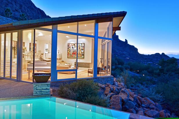 At twilight, an illuminated villa overlooks a private pool and the Arizona mountains.