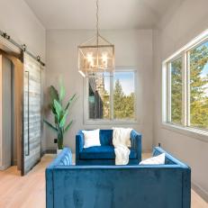 Modern Sitting Room With Dual Blue Loveseats and Elegant Pendant Light
