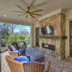 Brick-Floor Outdoor Sitting Area With Shiplap Ceiling and Stone Fireplace