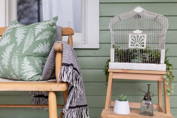 Vintage Birdcage With Succulents Inside on Outside Porch Beside Bench