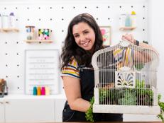 Woman Holds Upcycled Birdcage at Crafting Work Bench