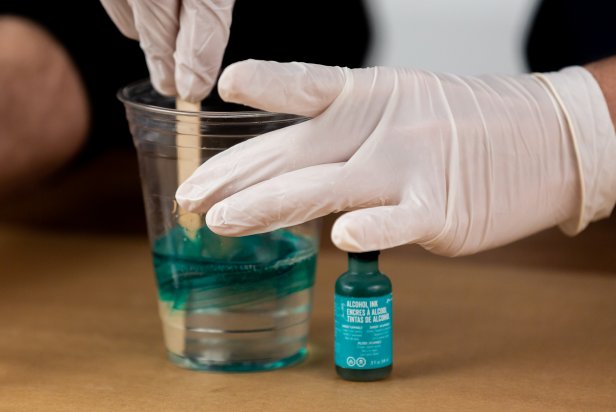 In one cup, add a few drops of teal alcohol ink and stir well to distribute the color.