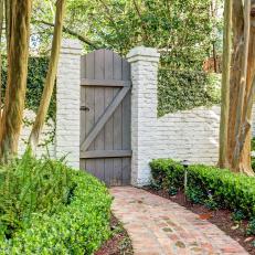 Brick Path Leading to Wooden Gate in Painted Brick Wall 