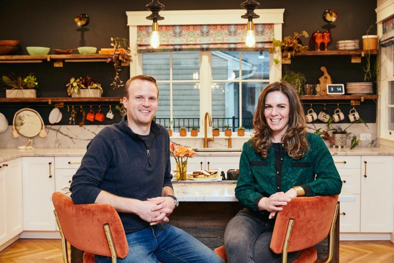 Bill and Kate Pearce sit in orange chairs at their kitchen island.