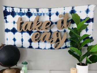 Cardboard Sign Against Blue and White Tie Dye Tapestry