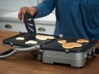 cooking heart-shaped pancakes on a griddle