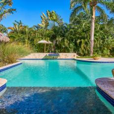 Palm Trees and a Flagstone Walkway Surrounds a Large Swimming Pool