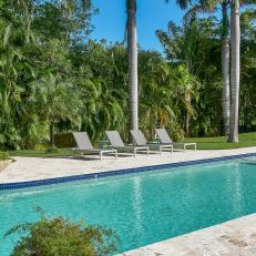 Large Swimming Pool Is Surrounded By a Flagstone Pool Deck and Tropical Foliage