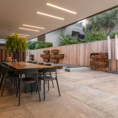 Covered Stone Patio Features a Wood Dining Table and a Small Sitting Area