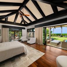A Large Bedroom Features Vaulted Ceilings With Exposed Beams and Sliding Doors to the Backyard