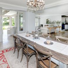 Open Concept Dining Room Features a Wood Table and a Crystal Chandelier 