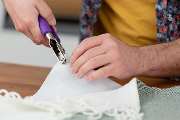 Cut the waterproof vinyl material to fit your blanket. Layer the blanket over the vinyl so the edges fit together. Use heavy duty snap pliers to punch a hole through both materials starting with one corner and about an inch away from the edge.