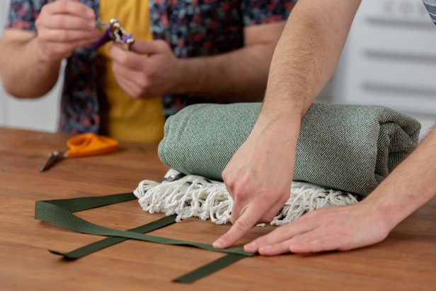 Cut two 10-inch pieces of nylon. Then, measure out and cut two nylon straps to carry the blanket. Cut one the exact size of the width, and cut the other just a little bit longer. Now create the letter “H” with the cut nylon pieces. Do this by laying the two longer straps vertically and parallel to each other, about 8-inches apart. Then, add two smaller straps horizontally across the longer vertical pieces.