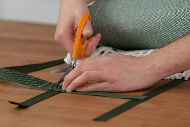 Cut two 10-inch pieces of nylon. Then, measure out and cut two nylon straps to carry the blanket. Cut one the exact size of the width, and cut the other just a little bit longer. Now create the letter “H” with the cut nylon pieces. Do this by laying the two longer straps vertically and parallel to each other, about 8-inches apart. Then, add two smaller straps horizontally across the longer vertical pieces.