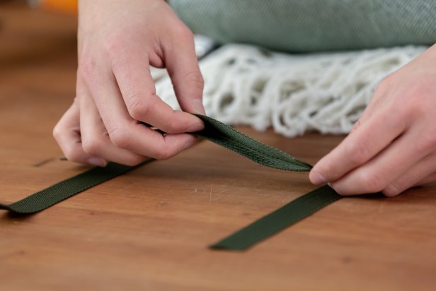 Measure out and cut two nylon straps to carry the blanket. Cut one the exact size of the width, and cut the other just a little bit longer. Now create the letter “H” with the cut nylon pieces. Do this by laying the two longer straps vertically and parallel to each other, about 8-inches apart. Then, add two smaller straps horizontally across the longer vertical pieces.