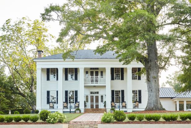 A Greek Revival-style home sits among mature trees in Alabama.