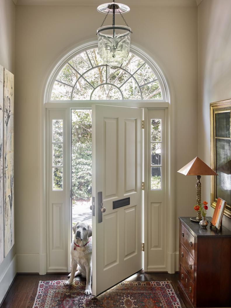 An entranceway features an arched door and oriental rug.