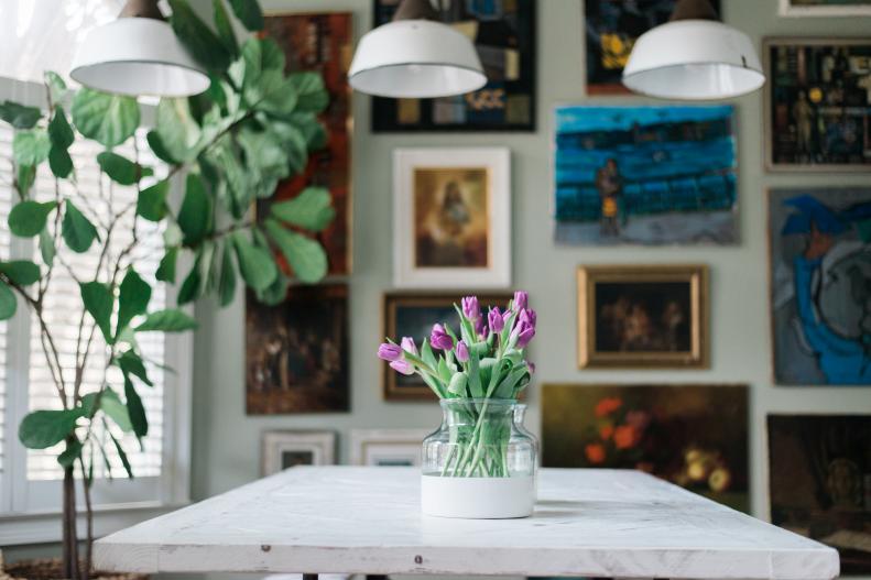 A home office features a wall of colorful oil paintings.