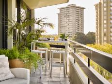 The condo balcony includes a table, chairs and plants.
