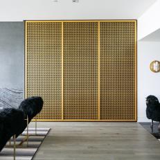 Custom Brass Accent Wall Acts As a Partition Between the Entry and the Living Room