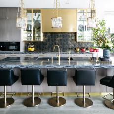 Modern Eat-In Kitchen Features Gold Pendants and a Marble Waterfall-Edge Island With Leather Barstools