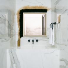 Bright Powder Room Features a Solid Marble Vanity With Black Fixtures and a Horse Hair Mirror