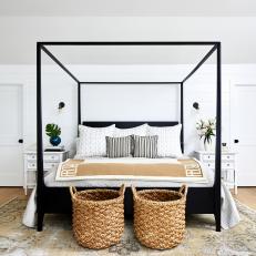 Bright Bedroom With a Shiplap Accent Wall Features a Black Four-Poster Bed and White End Tables