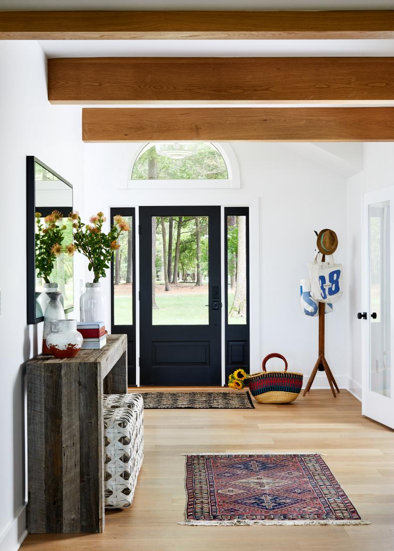 Bright Foyer Features a Black Front Door and Exposed Wood Beams