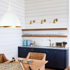 Open Concept Space Features a Shiplap Accent Wall and a Modern Bar With Gold Pendants and Open Shelving