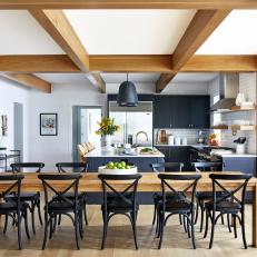 Bright Space Features a Large Wood Dining Table, Exposed Wood Beams and Black Cabinets