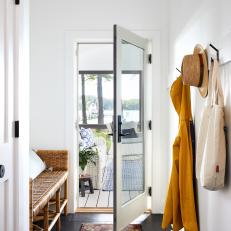 Bright Entryway Features a Wicker Bench, a Vintage Rug and a Modern Set of Hooks